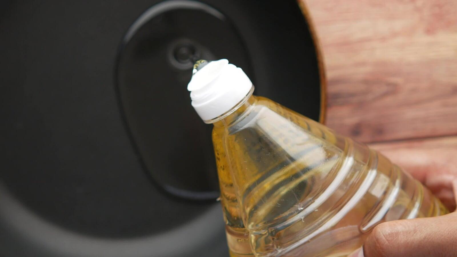 Hand holding a bottle of sunflower oil in a home kitchen, ready for use